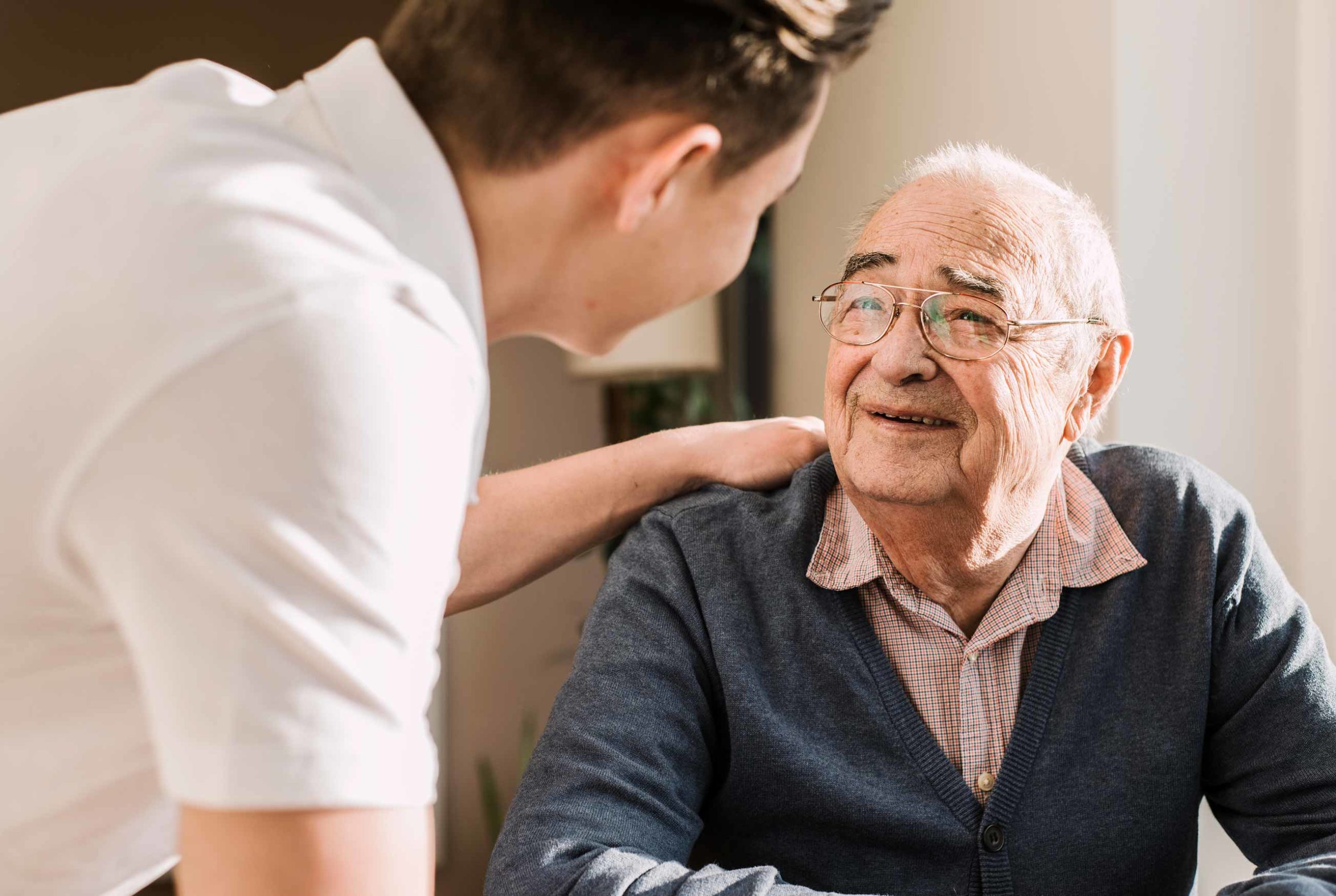 young male caregiver and retired male smiling